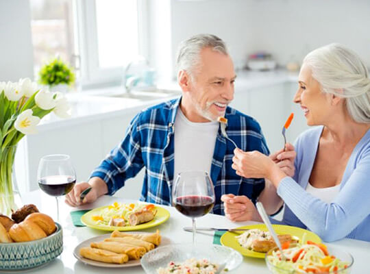 mature couple sitting in kitchen enjoying delicious meal