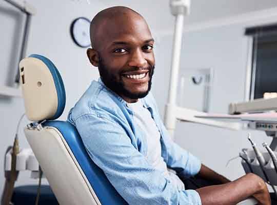 Man in blue shirt in dental chair smiling