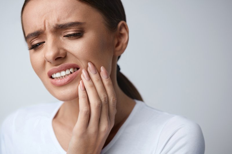 person with tooth sensitivity holding their cheek