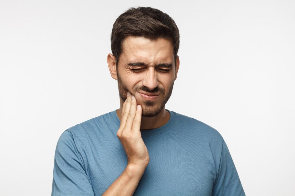 person with tooth pain holding cheek