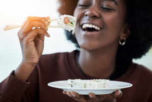 Woman grinning as she’s eating sushi 